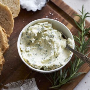 Rosermary Garlic Butter in a bowl on a wooden cutting board.