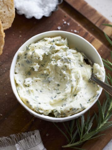 Rosermary Garlic Butter in a bowl on a wooden cutting board.