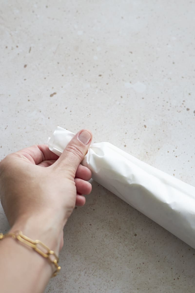 Fingers twisting the ends of the parchment paper roll.