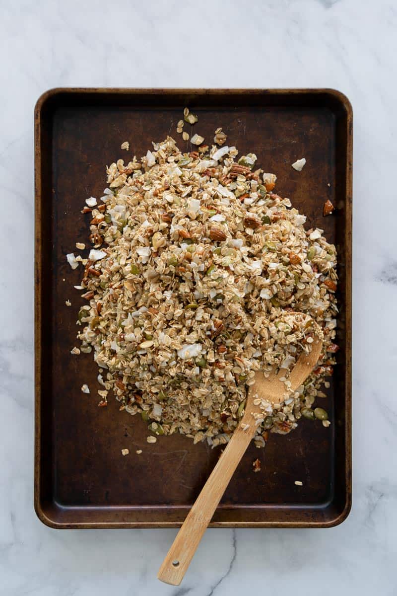 Granola on a baking sheet with wooden spoon. 