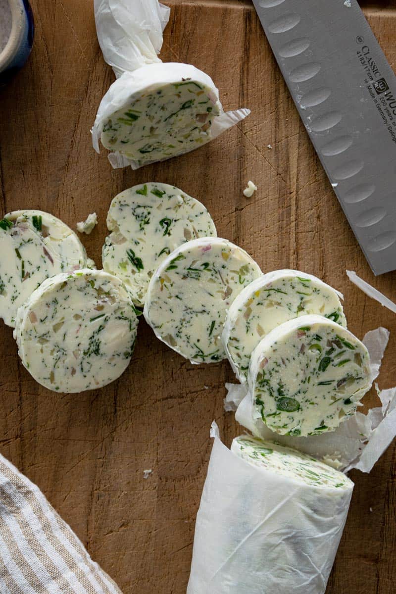 Rosemary Garlic Butter in slices on a wooden cutting board.