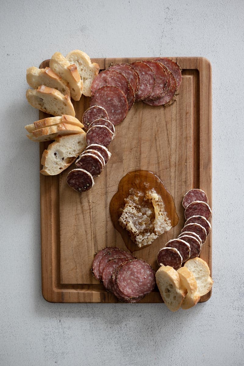 Breads and salami added at the edges of the charcuterie board. 