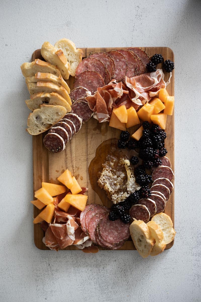 Large fruits added at the edges of the charcuterie board. 