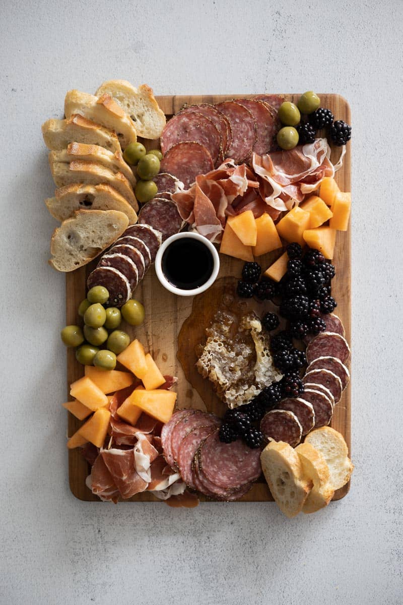 Olives and small fruits added to the board. 