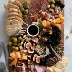 Summer charcuterie board on a tabletop with pale blue linen.