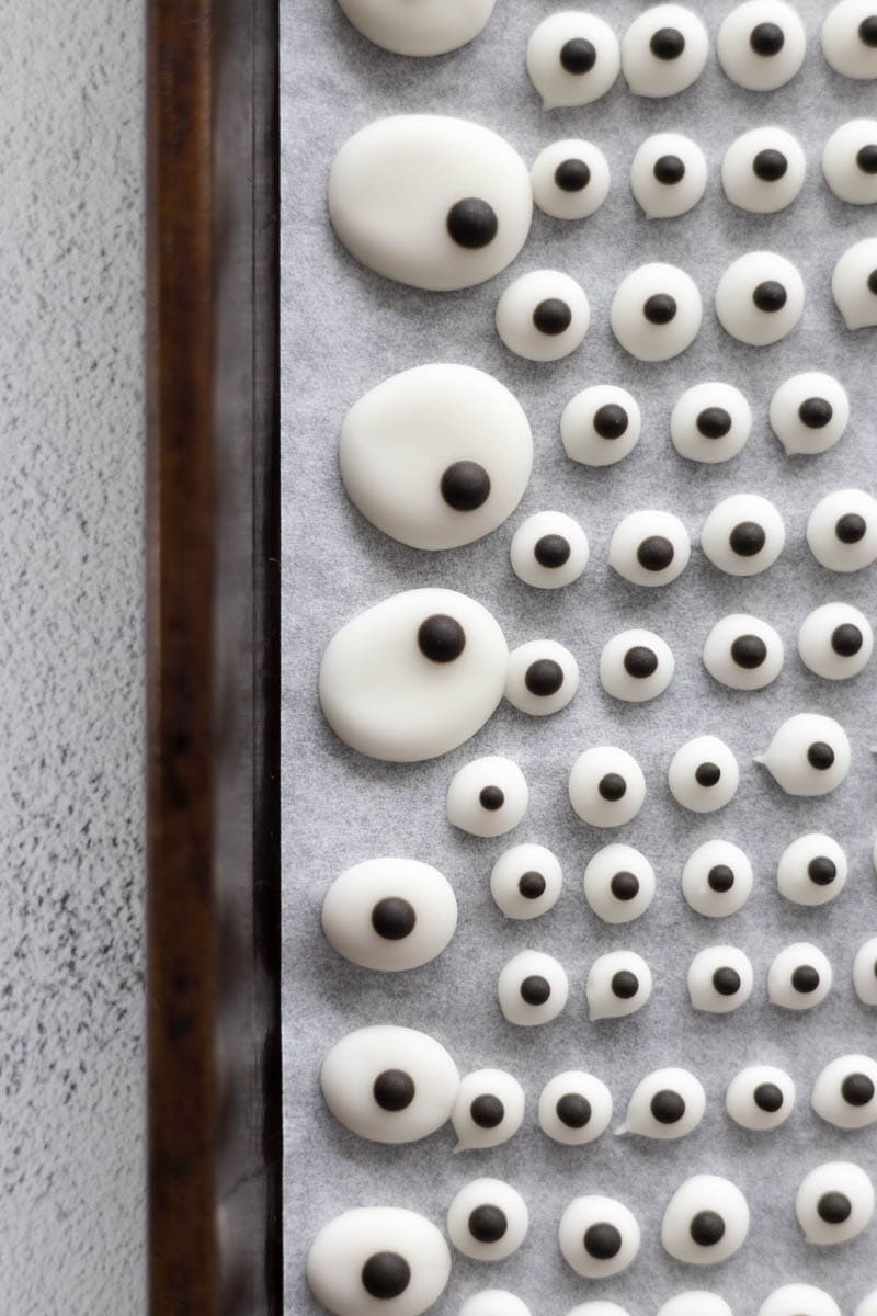 Irregularly shaped edible candy eyeballs on a baking sheet. 