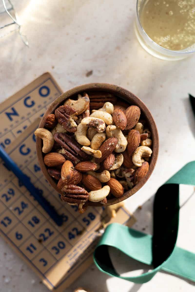 Spiced nuts with rosemary in a small wooden bowl.