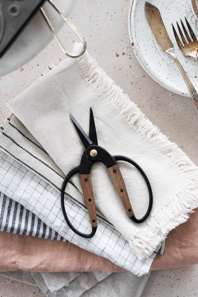 Small scissors on a stack of linens. 