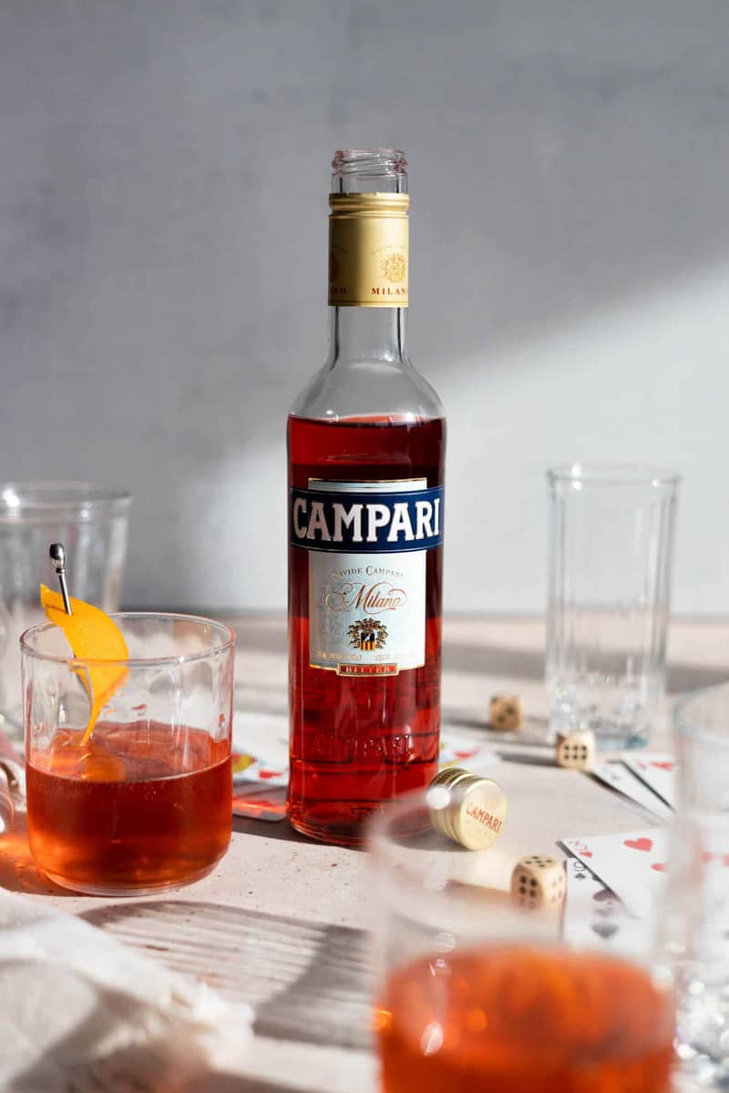 A bottle of Campari sitting among glassware.