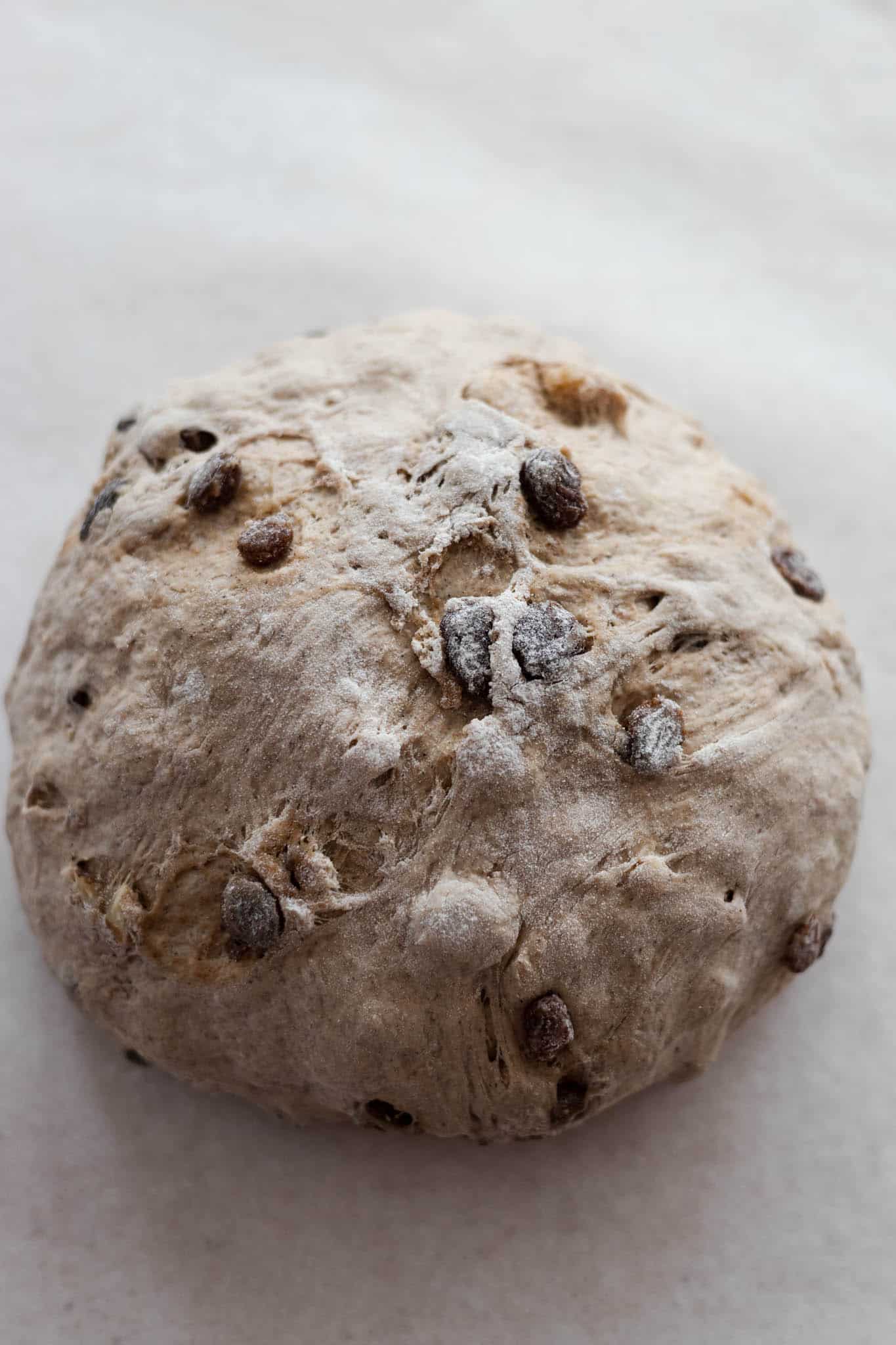 Once the dough has risen, form it into a ball and transfer to parchment paper. 