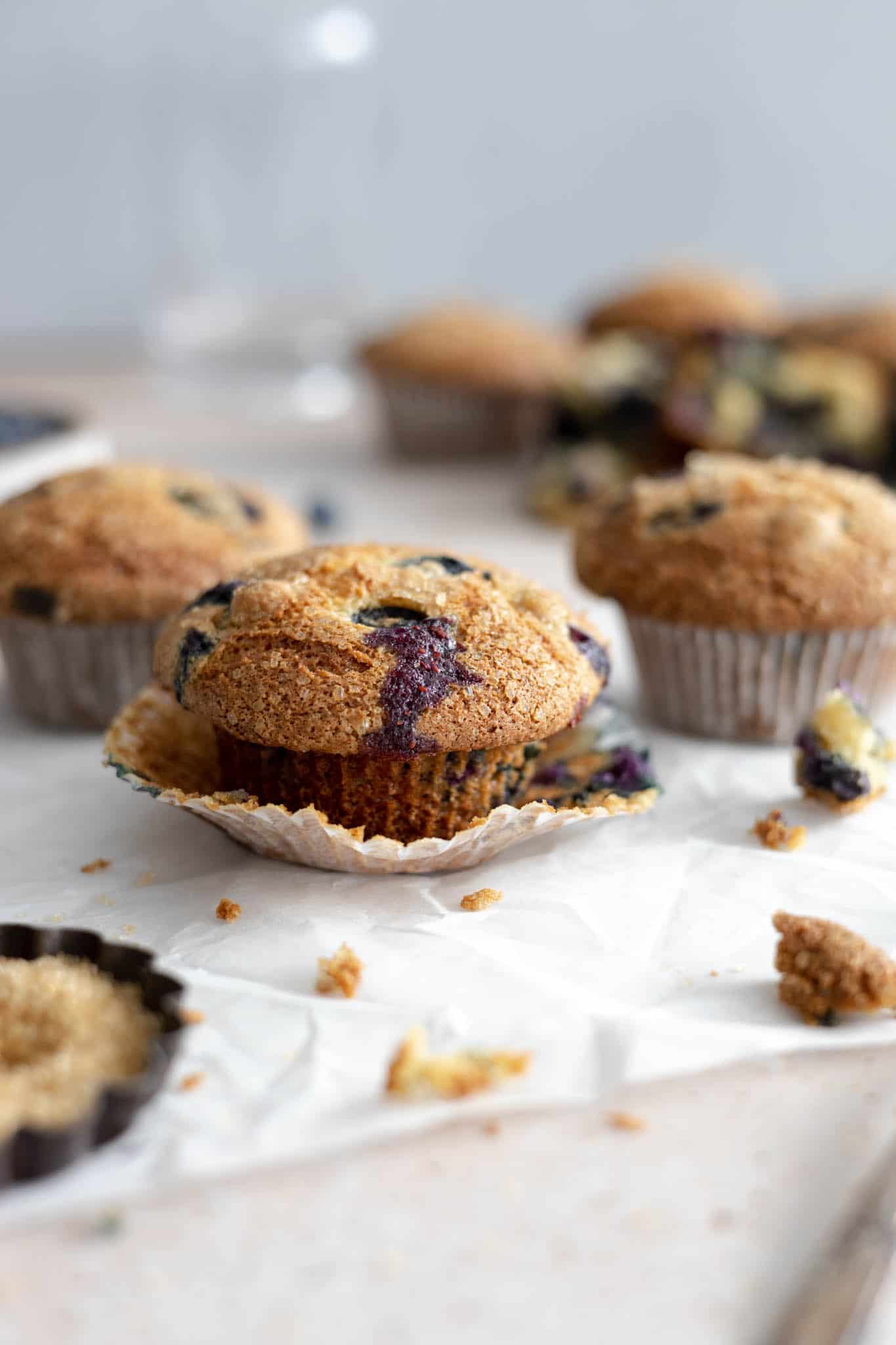 An unwrapped blueberry sour cream muffin on parchment paper. 