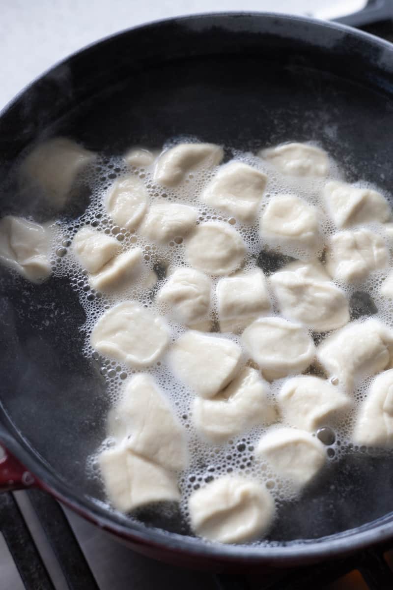 Sourdough pretzel bites boiling in water.