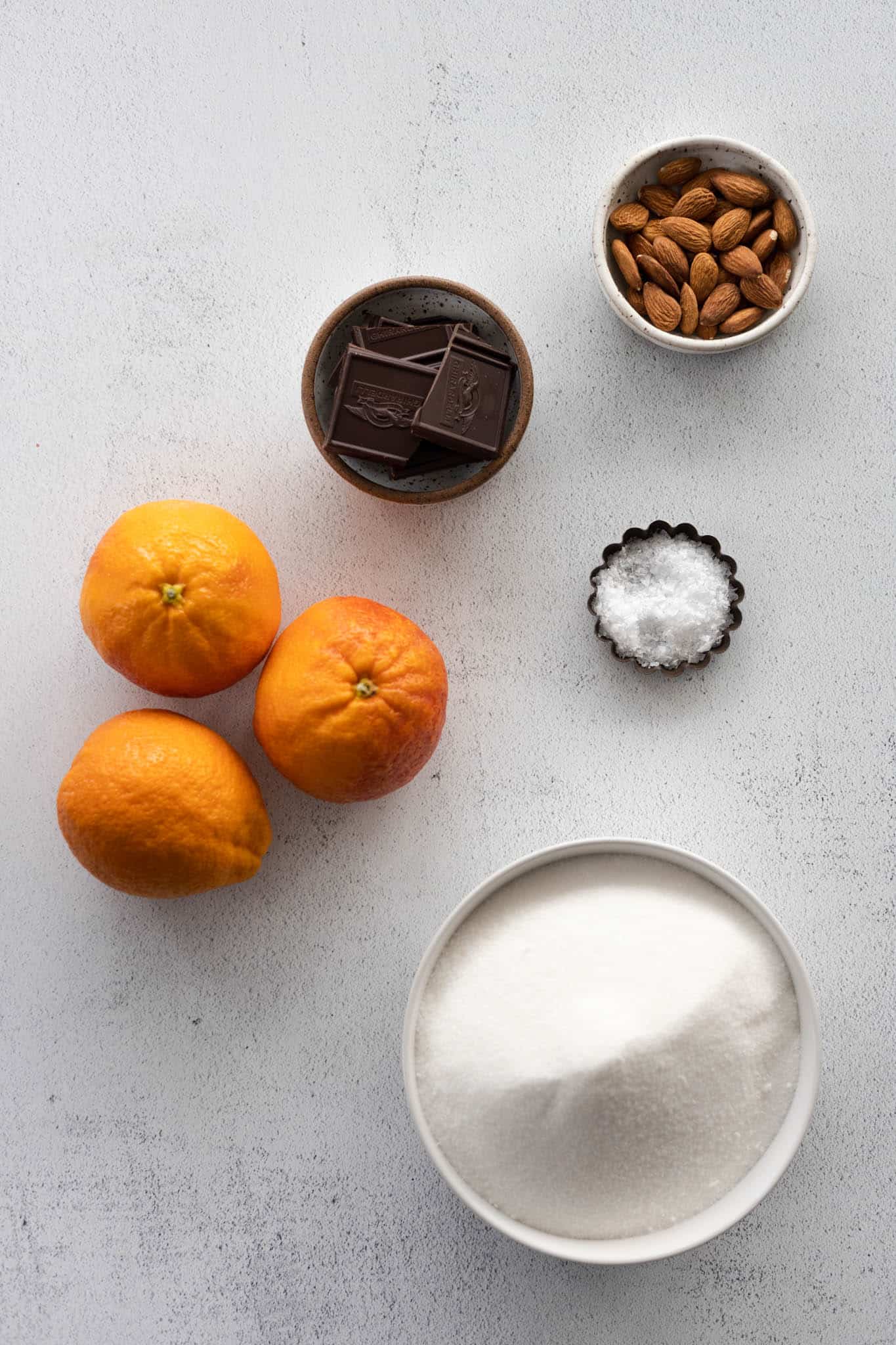 Ingredients for chocolate dipped orange slices in small bowls. 