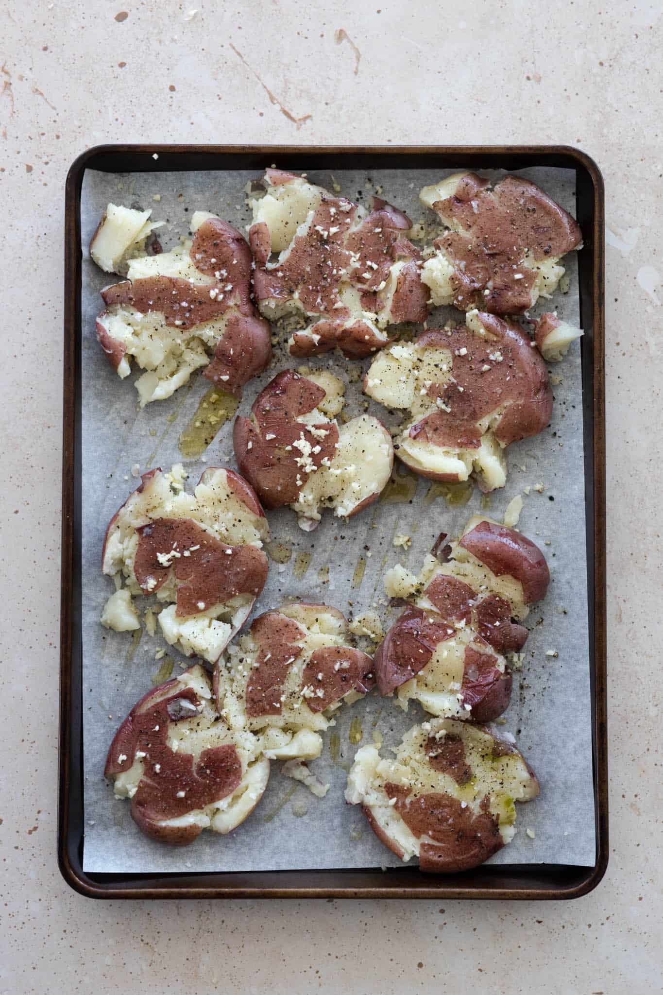 A tray of smashed potatoes ready for baking.