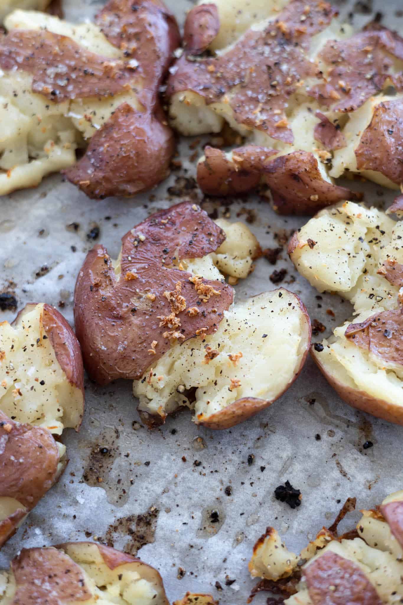 A closeup of smashed potatoes with roasted garlic.