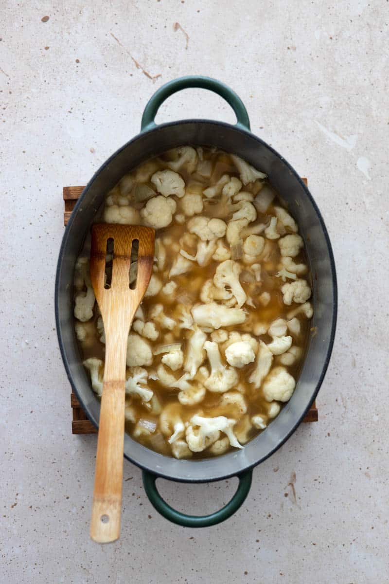 Cauliflower and chicken stock mixed in with the soup based in a Dutch Oven. 