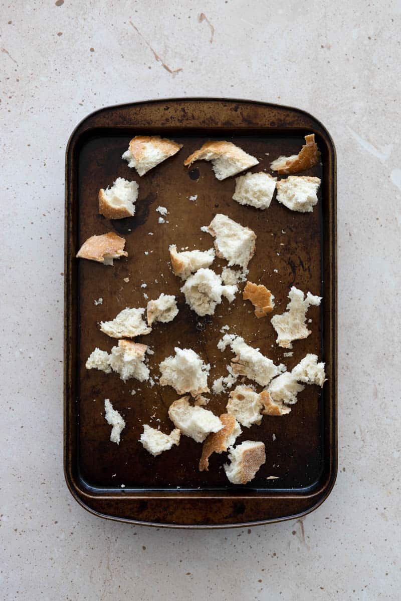 Torn chunks of bread on a baking sheet.