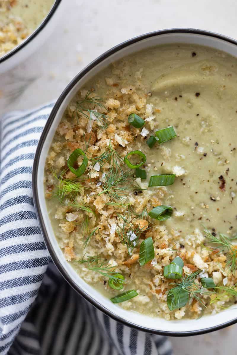 A closeup of Spinach Cauliflower Soup in a bowl with a blue and white striped linen.