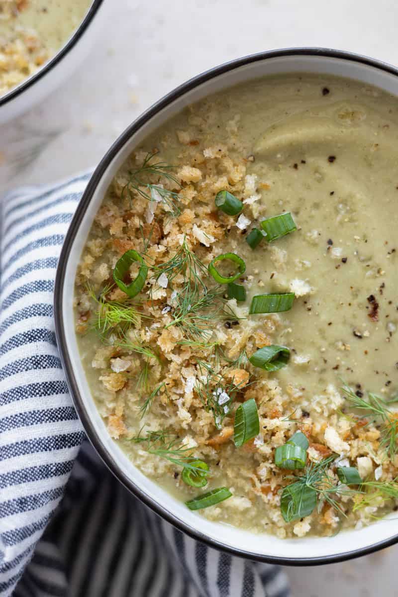 A closeup of Spinach Cauliflower Soup in a bowl with a blue and white striped linen. 