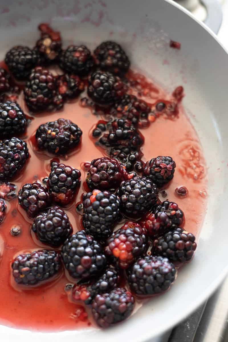 Blackberries starting to simmer in a small skillet.