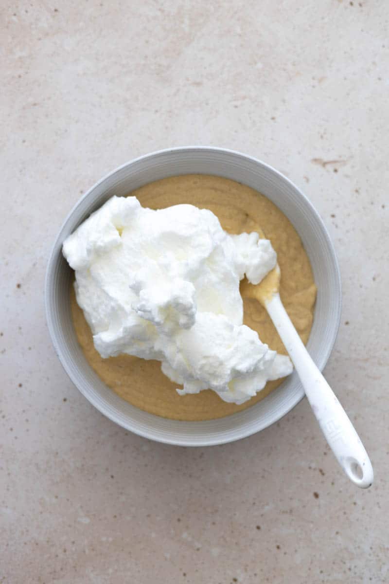 Egg whites added on top of the batter, ready for folding with a spatula. 