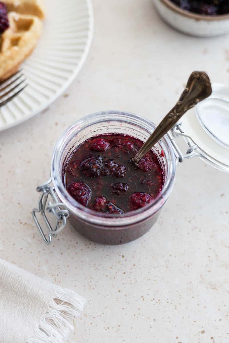 Blackberry Bourbon Maple Syrup in a jar with a spoon. 