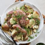 Smashed potatoes with green onions and dill on a white serving platter.