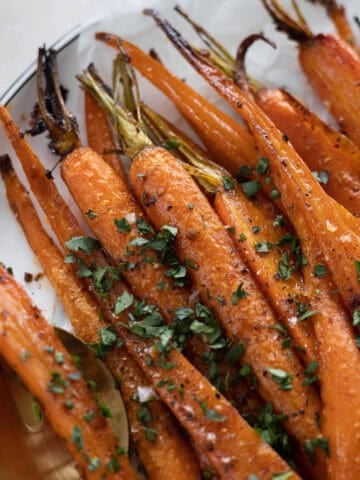 Honey Garlic Roasted Carrots in a pile on a white platter.