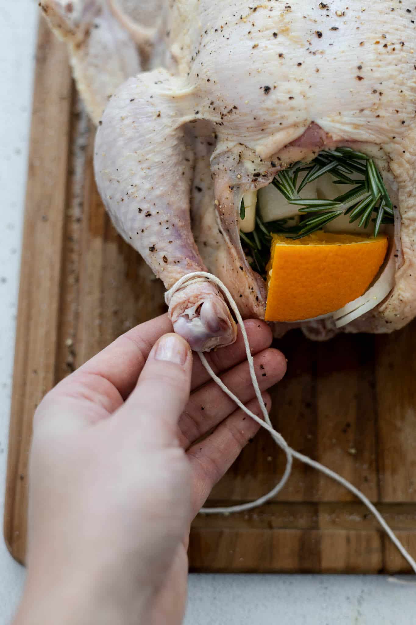 Kitchen twine tied around one leg of the stuffed chicken.