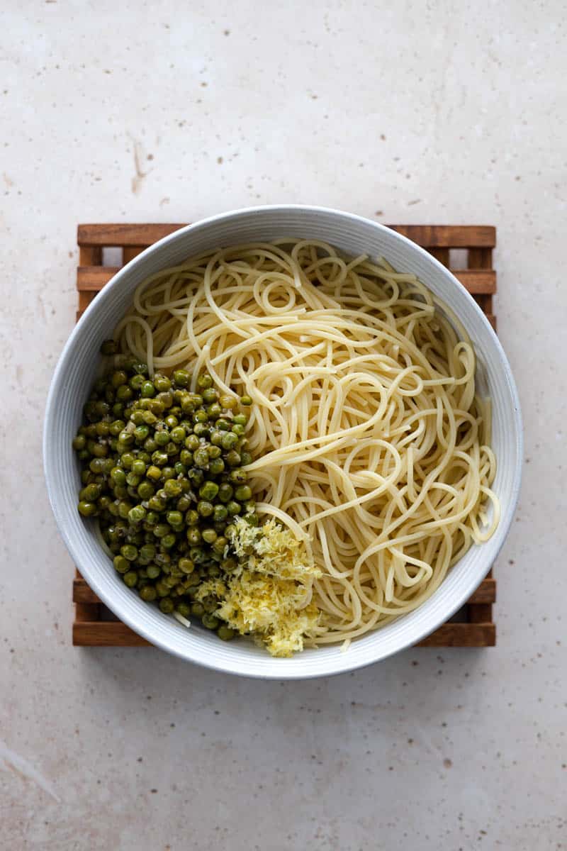 Pasta, peas and lemon zest in a bowl ready to mix.