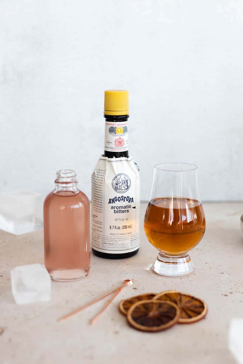 The ingredients for a Blood Orange Old Fashioned in glasses and bottles. 