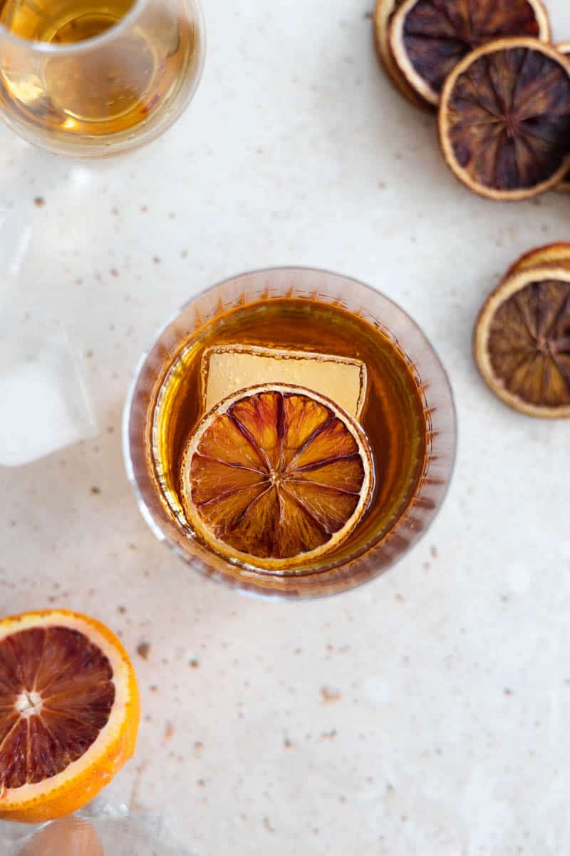 An overhead shot of a Blood Orange Old Fashioned with a blood orange slice and one large ice cube in the glass. 