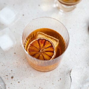 Blood orange old fashioned in a cocktail glass, garnished with dried blood orange.