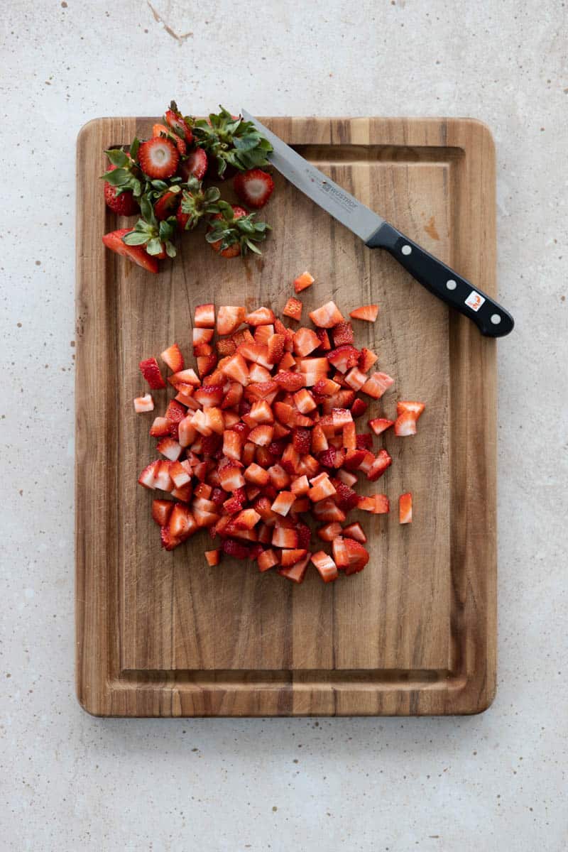 Chopped strawberries on a cutting board.