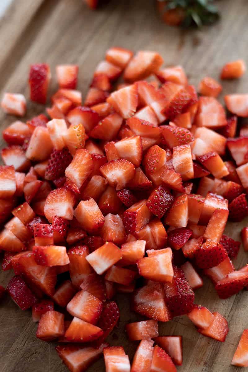 Closeup of chopped strawberries on a cutting board.