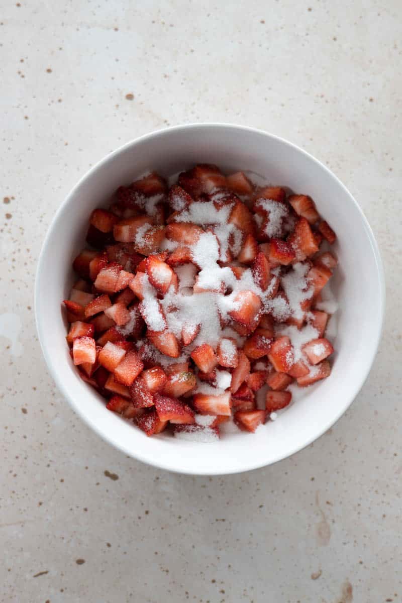 Diced strawberries with sugar sprinkled on top in a bowl.