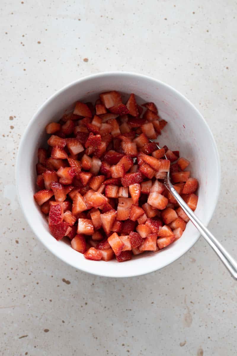 Strawberries mixed with sugar in a small bowl.