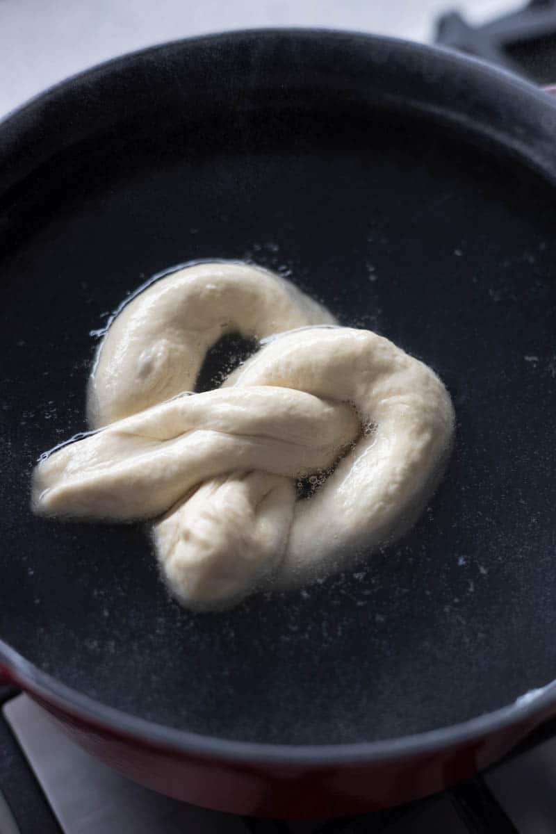 A pretzel boiling in a pot of water.