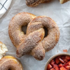 Cinnamon Sugar Pretzel on white parchment paper with a bowl of macerated strawberries.