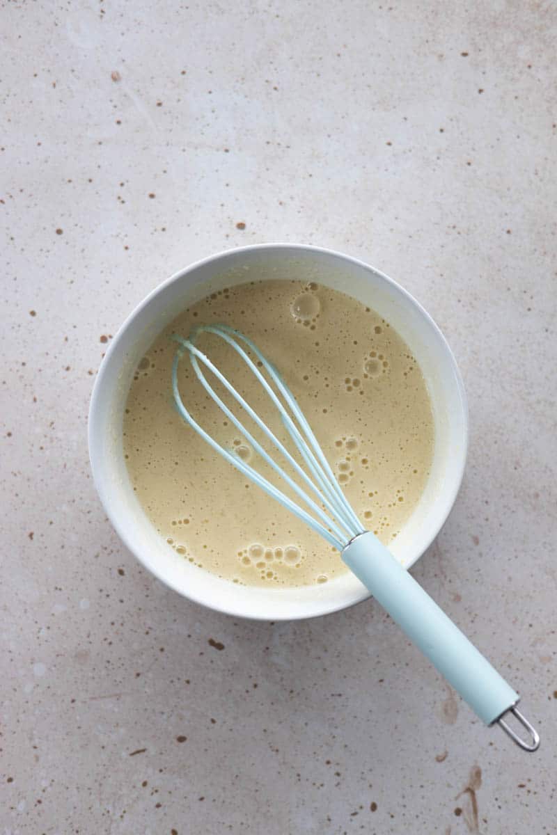 Wet ingredients stirred together in a large bowl with a whisk.
