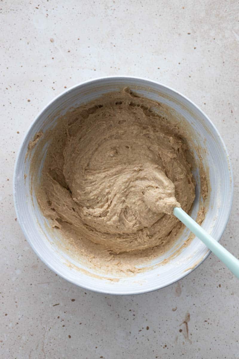 Wet and dry ingredients combined together in a large bowl with a spatula.