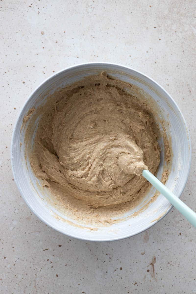 Wet and dry ingredients combined together in a large bowl with a spatula. 