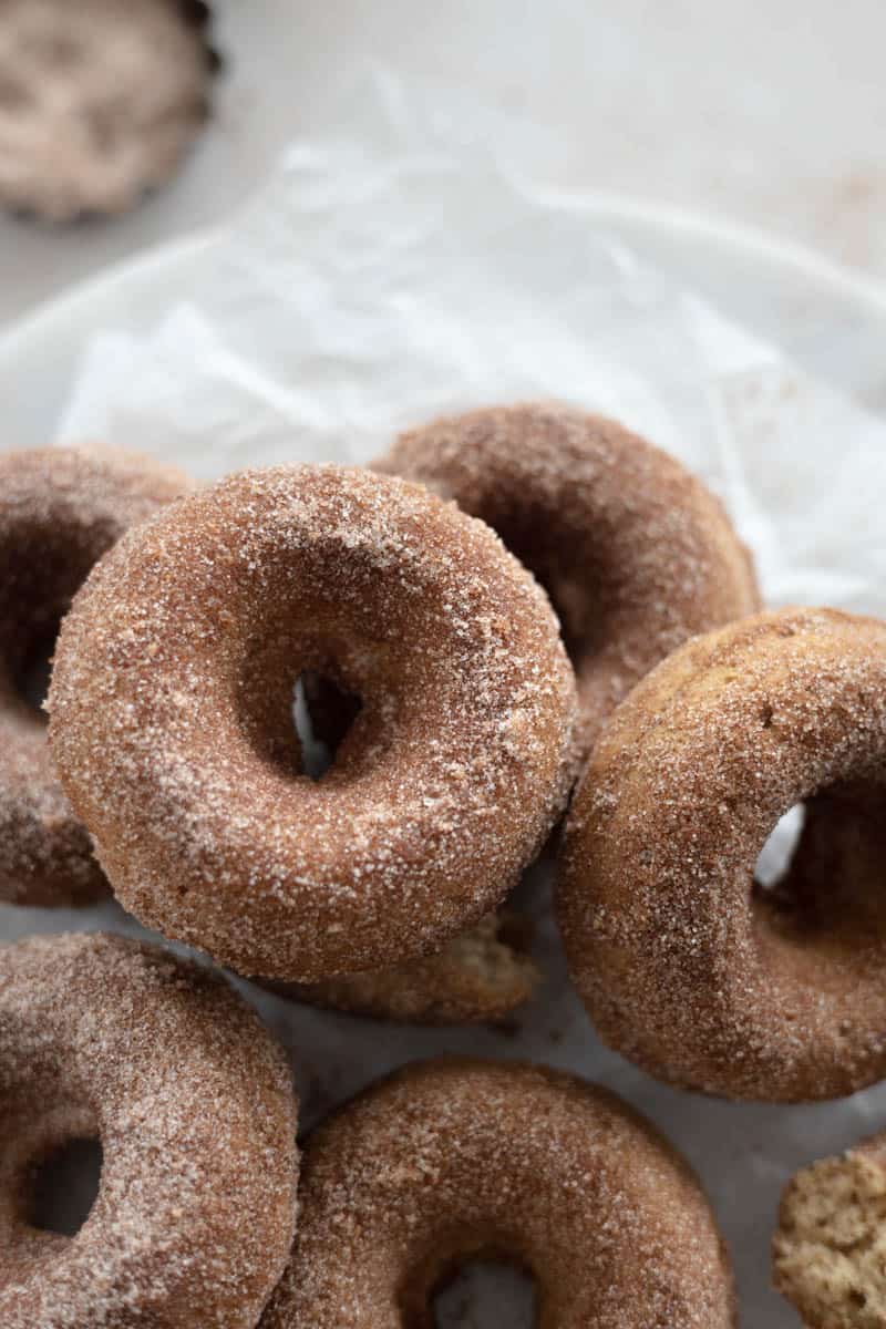A pile of donuts on a piece of parchment paper. 