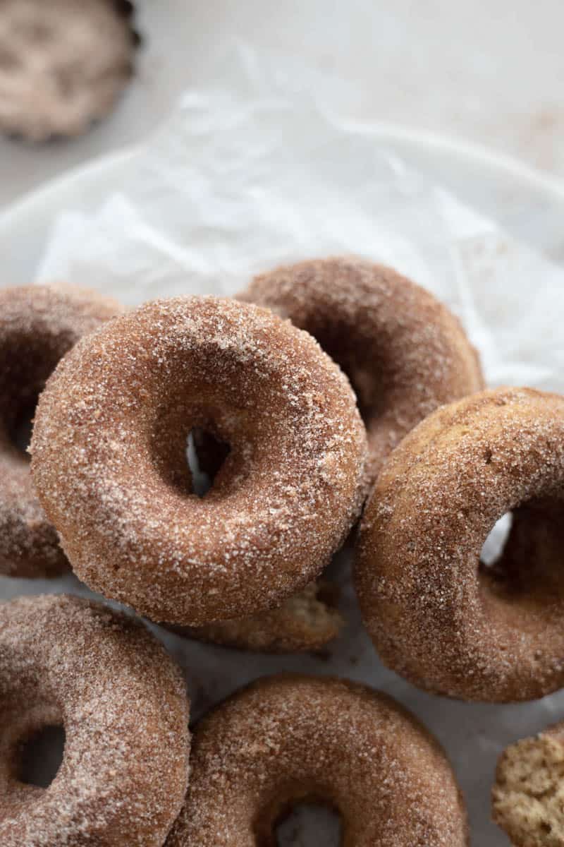 A pile of donuts on a piece of parchment paper.