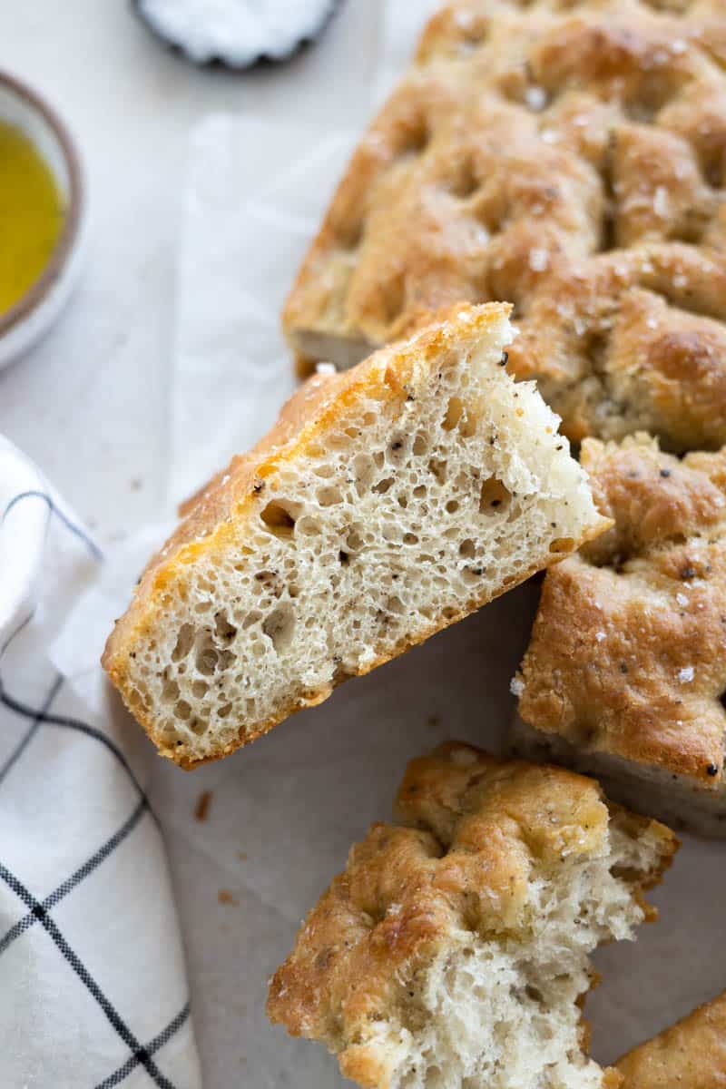 A side view of a slice of Black Pepper Focaccia with bubbly air pockets. 