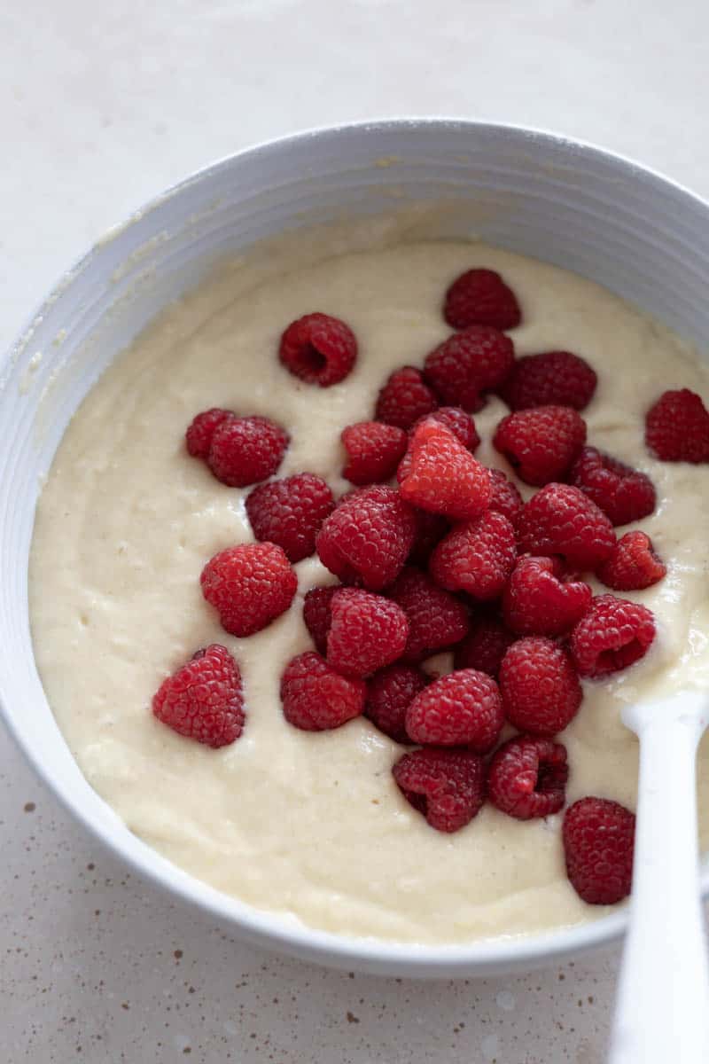 A closeup shot of the fresh raspberries added to the bowl with the batter.