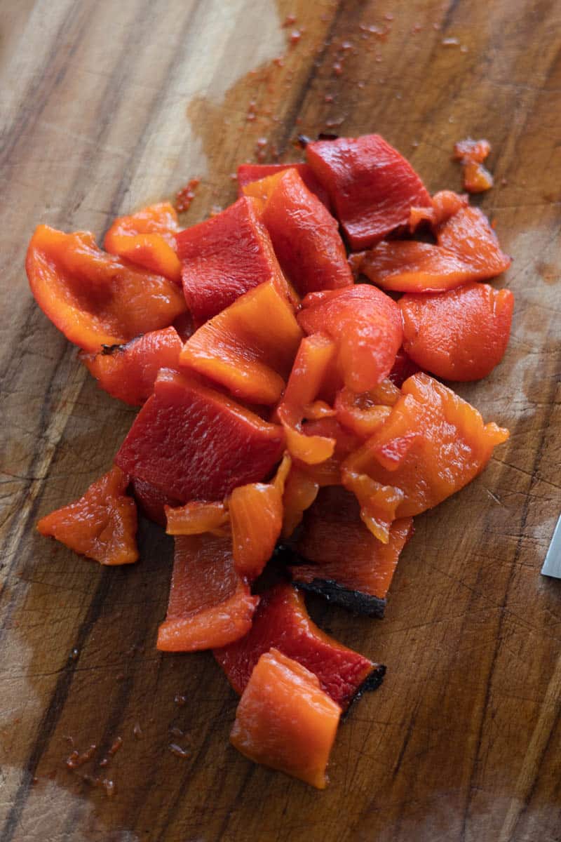 Roasted red peppers cut on a wooden cutting board.