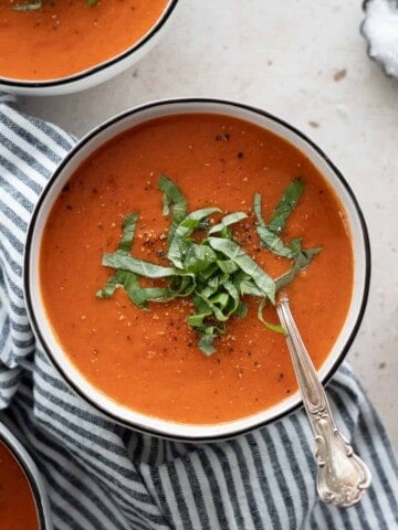 Roasted red pepper and tomoato soup on a bowl with a spoon.