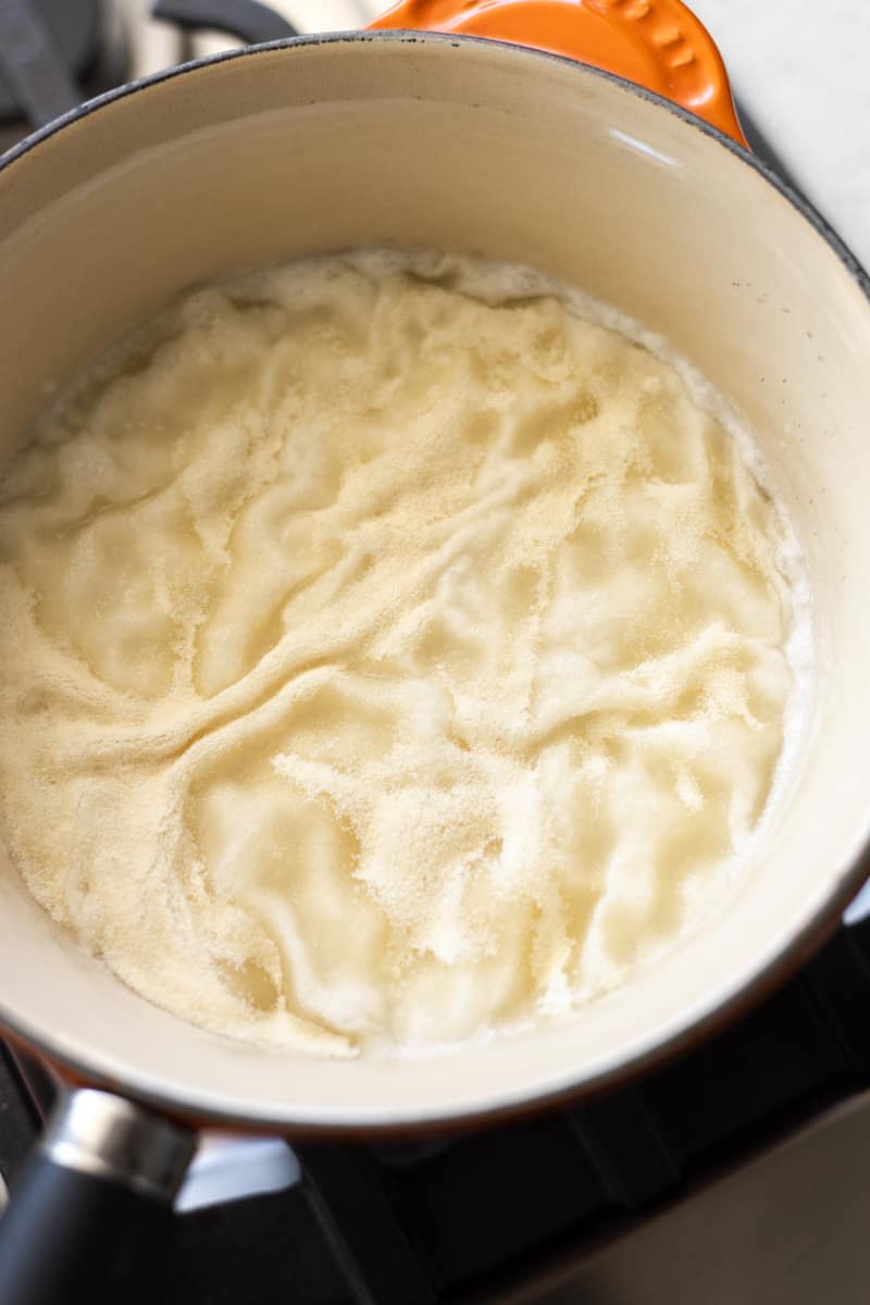 Wrinkled gelatin on the surface of the milk in a sauce pan. 