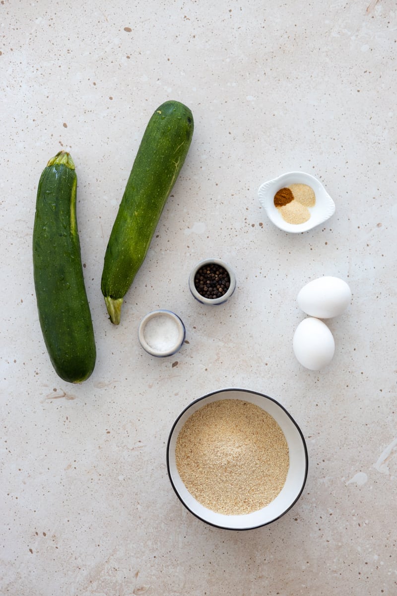 Ingredients for baked zucchini slices in small bowls. 